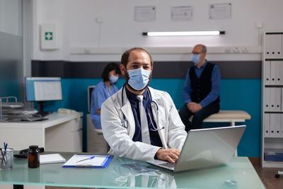 Doctor wearing mask using laptop