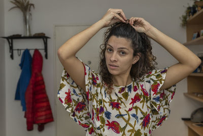 Portrait of young woman standing against wall