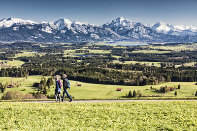 People walking amidst field against mountains
