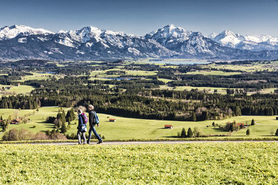 Rear view of people on field against mountains