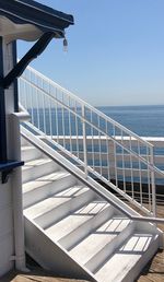 Staircase by sea against clear sky