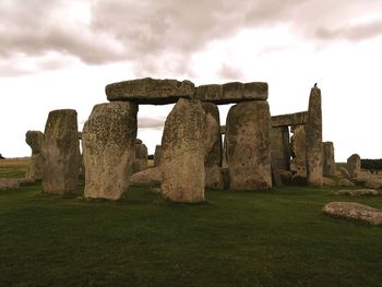 Old ruins on field against cloudy sky