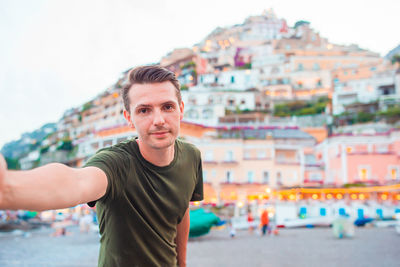 Portrait of young man standing against cityscape