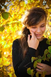 Close-up of young woman against yellow leaves during autumn