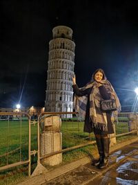 Optical illusion of woman standing against illuminated pisa tower 