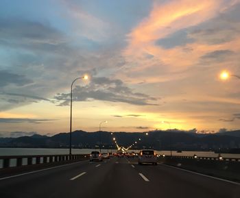 Road leading towards mountains against cloudy sky