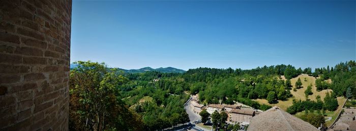 Panoramic view of trees and buildings against blue sky