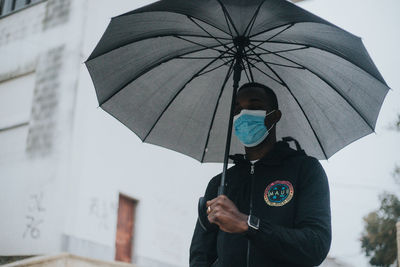 Man with umbrella standing on rainy day