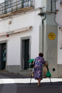 Rear view of woman walking on footpath against building