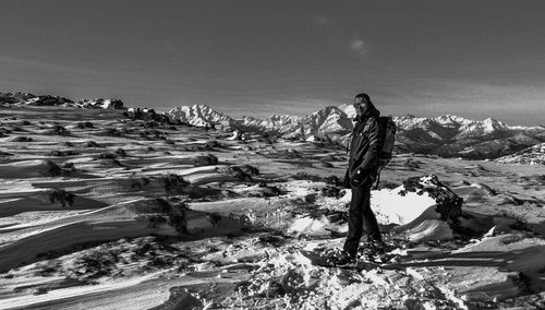 Young woman standing on rock against sky during winter