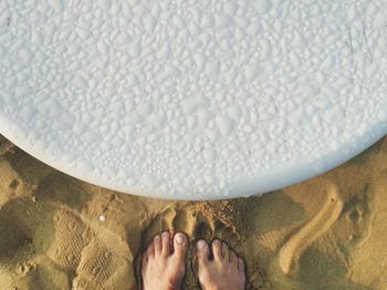 Low section of person standing by wet white table at beach