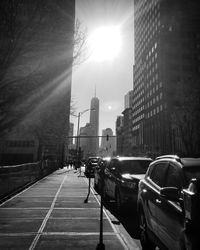 Cars on road by buildings against sky in city