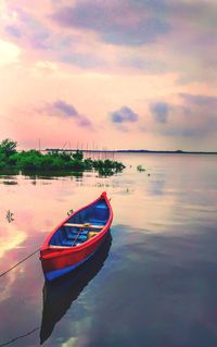 Boat moored in sea against sky during sunset