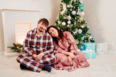 Young couple sitting on christmas tree