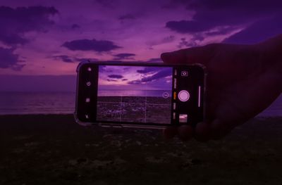 Low angle view of camera on mobile phone against sunset sky