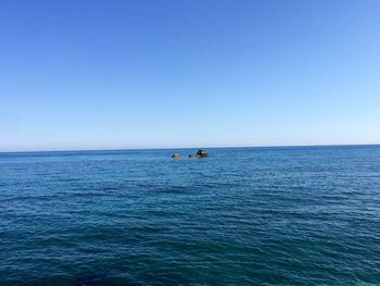 Boat sailing in sea against clear sky