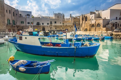 Boats moored in sea against buildings in city