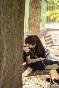 Mother and son or couple enjoying time together on bench, hugging  with sun flare. love care.