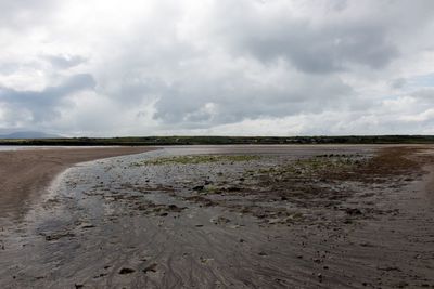 Scenic view of beach against cloudy sky