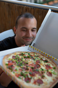 Smiling man looking at pizza at restaurant