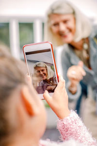 Granddaughter taking photograph of grandmother in mobile phone