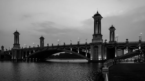 Bridge over river by buildings against sky in city