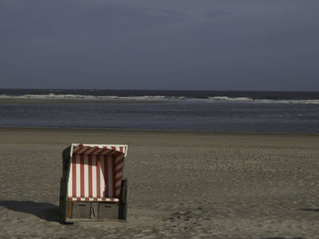 Chair on beach against sky