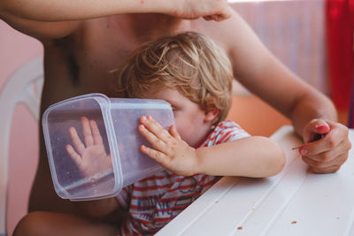 Midsection of shirtless boy sitting at home