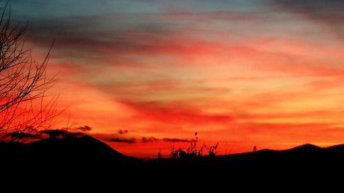 Silhouette landscape against orange sky