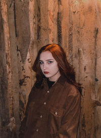 Portrait of young woman standing against wall