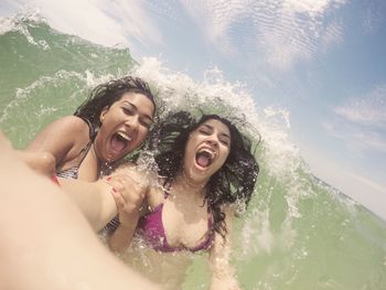 Cheerful young women enjoying sea waves