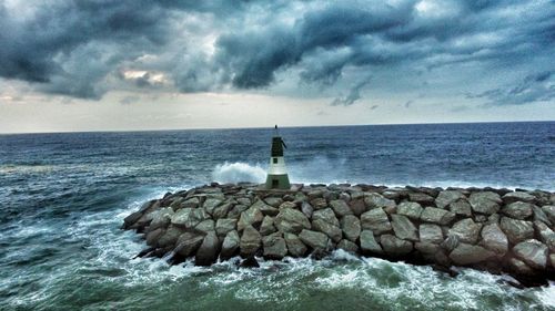 Lighthouse by sea against sky