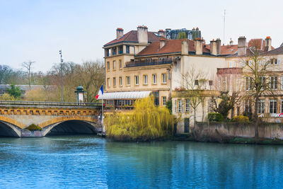 Bridge over river by buildings in city against sky