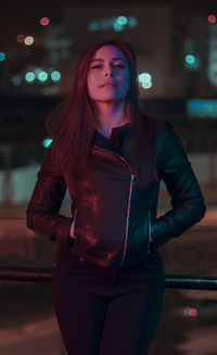 Beautiful young woman standing in city at night