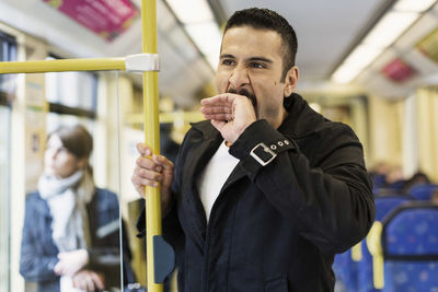 Bored young man yawning in tram