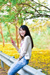 Side view of smiling young woman against plants