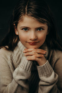 Close-up portrait of cute smiling girl against black background