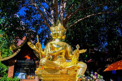 Low angle view of statue against trees at temple