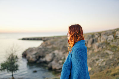 Woman looking at sea against sky during sunset