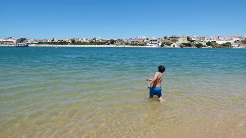 Full length of shirtless man on sea against sky