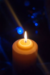 Close-up of lit candle in darkroom