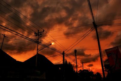 Low angle view of silhouette electricity pylon against sky during sunset