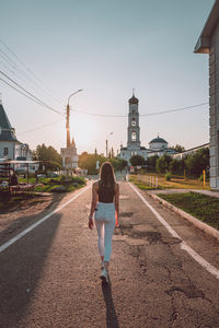 Rear view of woman walking on road in city