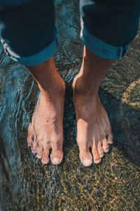 Low section of man standing at beach