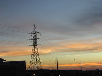 Low angle view of silhouette electricity pylon against sky during sunset