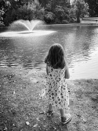 Rear view of of child standing at a pond