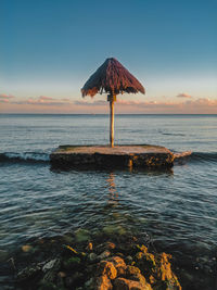 Scenic view of sea against sky during sunset and natural umbrella