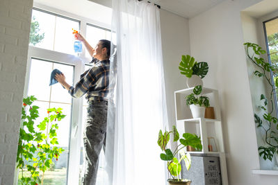 Rear view of woman standing by window