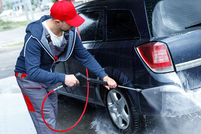 Side view of man cleaning car