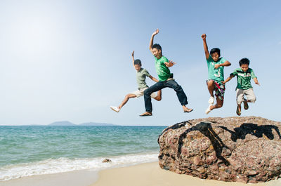 People jumping at beach against clear sky